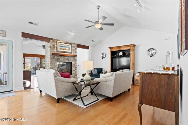 living area featuring light wood-type flooring, visible vents, a multi sided fireplace, lofted ceiling, and ceiling fan