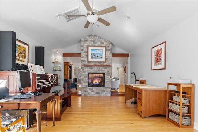 living room featuring visible vents, ceiling fan, a stone fireplace, and light wood-style floors