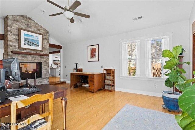 home office featuring visible vents, ceiling fan, a multi sided fireplace, lofted ceiling, and wood finished floors