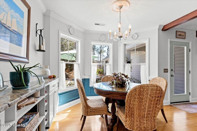 dining area with baseboards, visible vents, light wood finished floors, an inviting chandelier, and ornamental molding