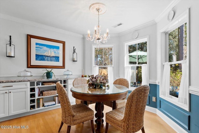 dining area with visible vents, a chandelier, ornamental molding, and light wood finished floors