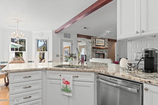 kitchen with white cabinets, dishwasher, a fireplace, and a sink