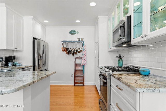 kitchen with white cabinets, light stone counters, light wood-style floors, and appliances with stainless steel finishes