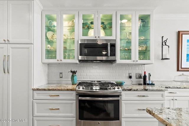 kitchen featuring decorative backsplash, appliances with stainless steel finishes, and white cabinetry