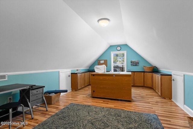 office with vaulted ceiling and light wood-style flooring