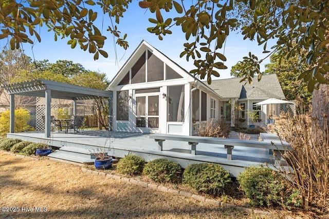 rear view of house with a pergola, a sunroom, and a wooden deck