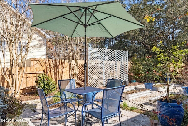 view of patio / terrace with a garden, outdoor dining space, and fence