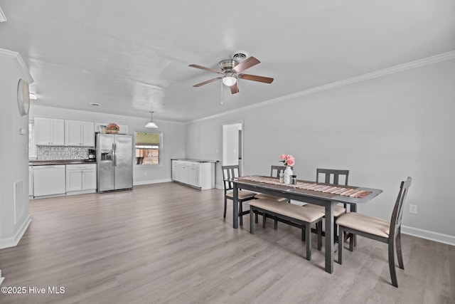 dining area featuring crown molding, light wood-style floors, and baseboards