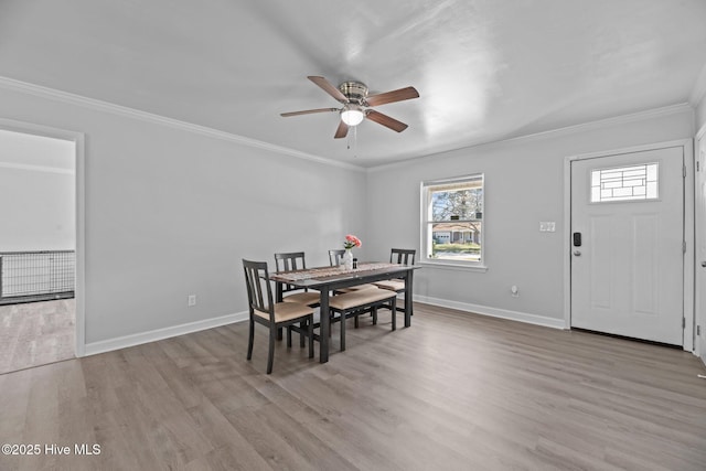 dining space with baseboards, a ceiling fan, wood finished floors, and crown molding