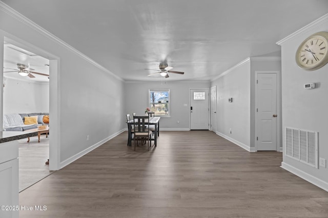 unfurnished dining area featuring visible vents, crown molding, baseboards, wood finished floors, and a ceiling fan