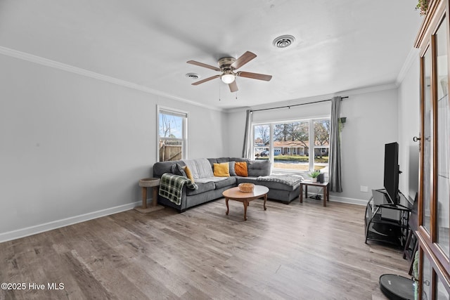 living area featuring visible vents, baseboards, wood finished floors, and crown molding