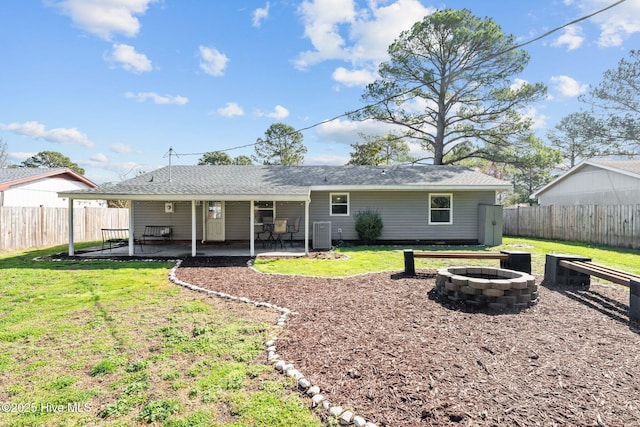 back of house featuring a fire pit, a lawn, and a fenced backyard