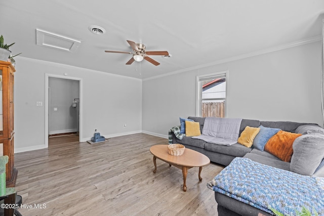 living room featuring attic access, visible vents, light wood finished floors, and ornamental molding