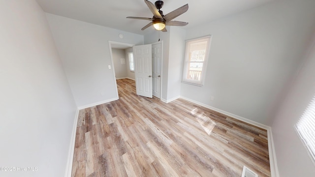 spare room featuring visible vents, light wood-style flooring, baseboards, and ceiling fan