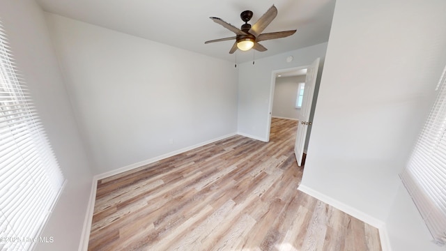 spare room featuring light wood-style flooring, a ceiling fan, and baseboards