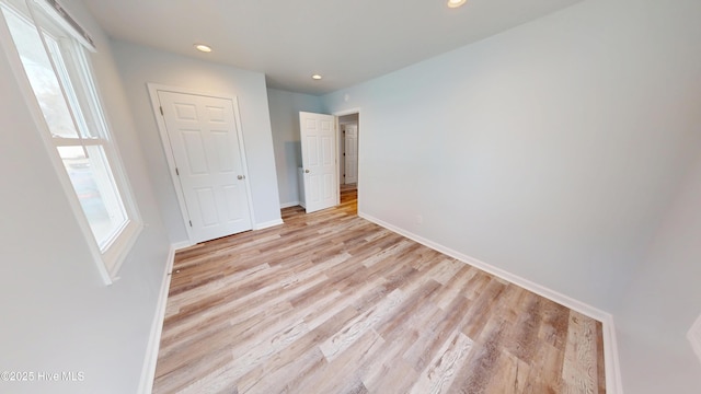 unfurnished bedroom with recessed lighting, light wood-style flooring, and baseboards