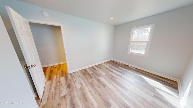 unfurnished room with visible vents, recessed lighting, light wood-type flooring, and baseboards