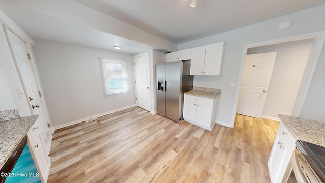 kitchen featuring light wood-style flooring, light stone counters, stainless steel appliances, white cabinets, and baseboards