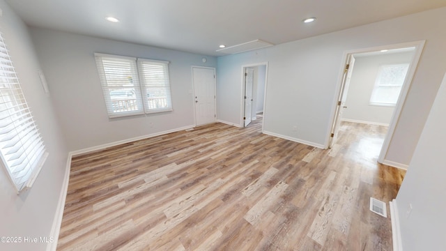 interior space with attic access, light wood-style flooring, plenty of natural light, and visible vents