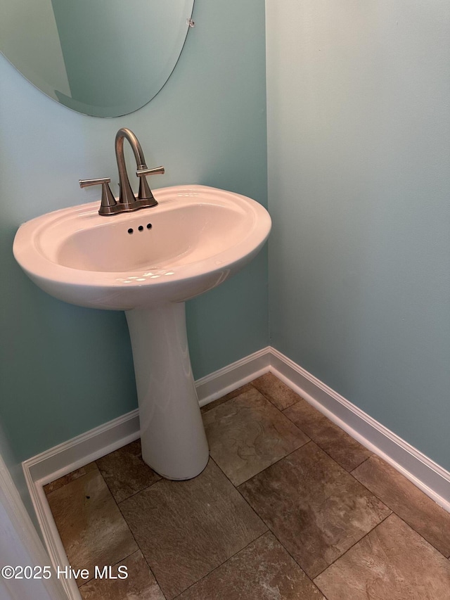 bathroom featuring baseboards, a sink, and tile patterned flooring