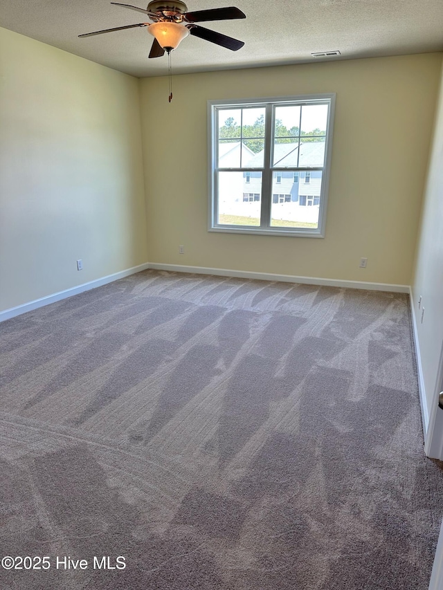 carpeted empty room with baseboards, a ceiling fan, a textured ceiling, and visible vents