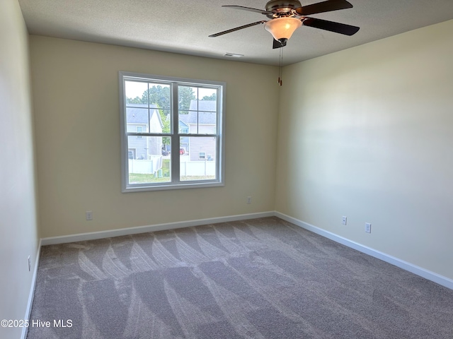 carpeted spare room with baseboards, a ceiling fan, a textured ceiling, and visible vents