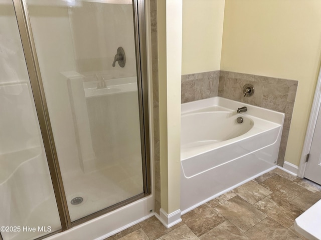 full bath featuring baseboards, a stall shower, and a bath