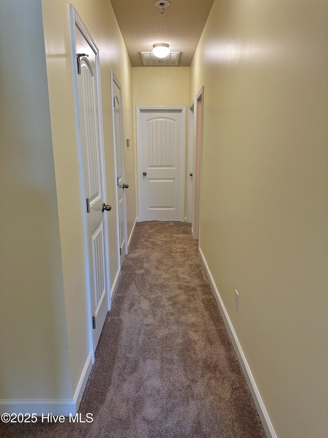 corridor featuring baseboards and carpet flooring