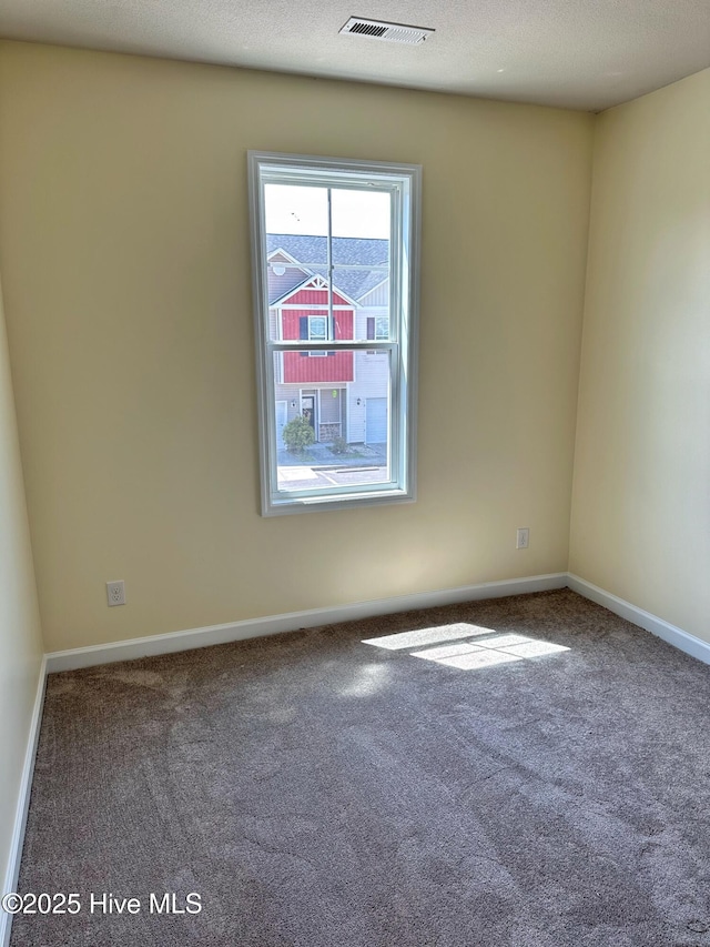 spare room featuring baseboards, carpet flooring, and visible vents