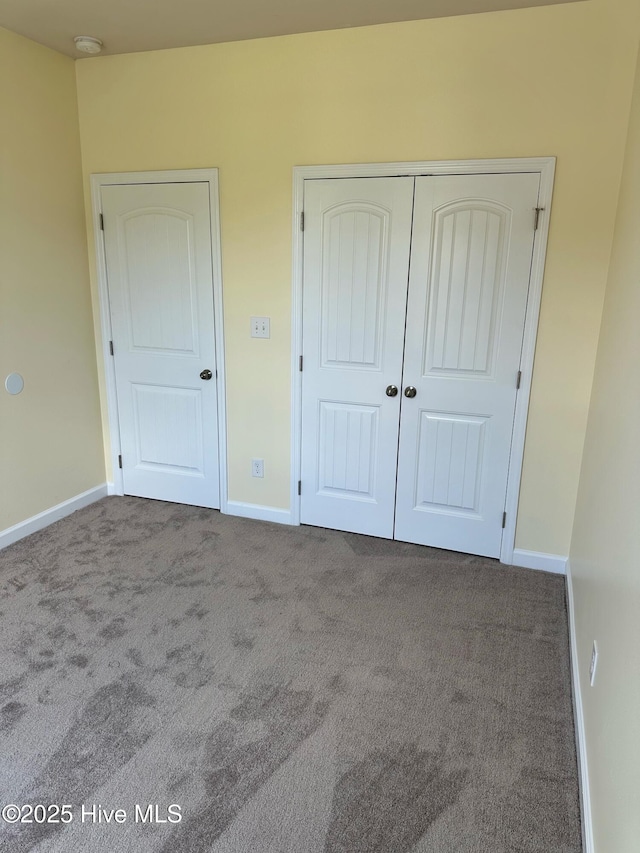 unfurnished bedroom with carpet flooring, baseboards, and a closet