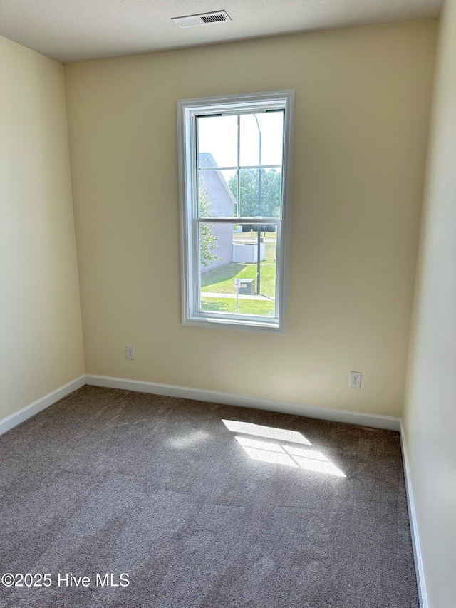 empty room featuring baseboards, carpet flooring, and visible vents