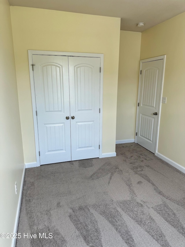 unfurnished bedroom featuring carpet floors, baseboards, and a closet