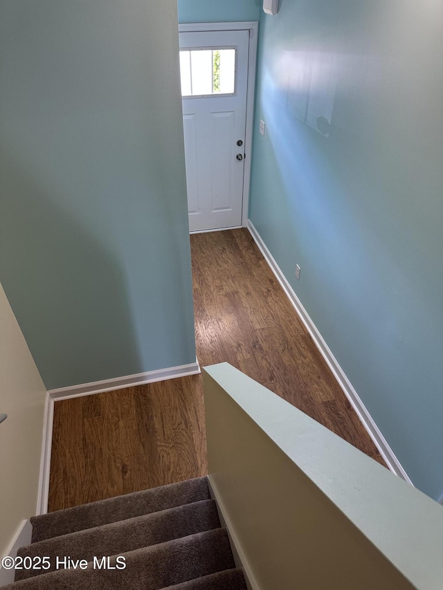 entryway featuring baseboards, wood finished floors, and stairway