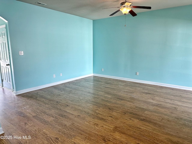 unfurnished room with dark wood-style flooring, a ceiling fan, baseboards, and visible vents