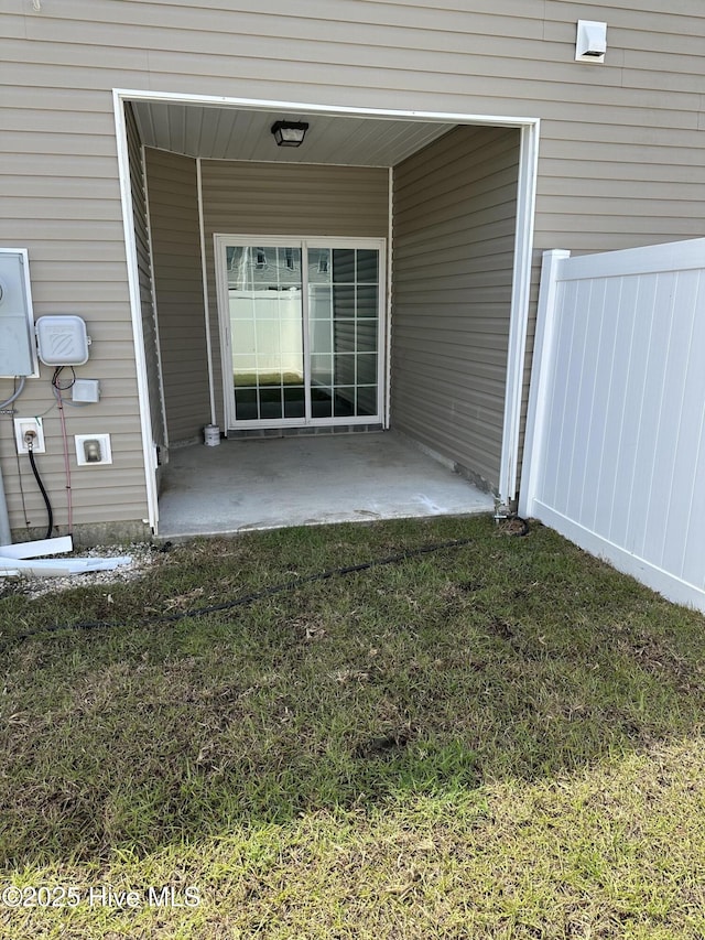 doorway to property featuring a patio, fence, and a yard