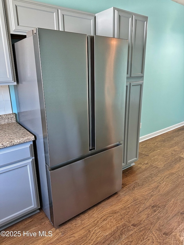 kitchen featuring freestanding refrigerator, dark wood-style flooring, baseboards, and gray cabinets