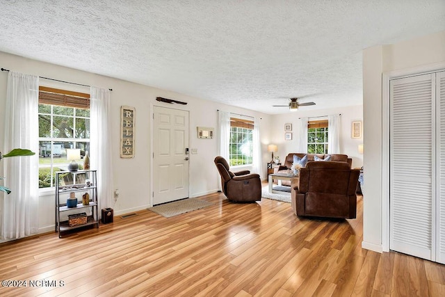 living room featuring a wealth of natural light, light wood finished floors, and a textured ceiling