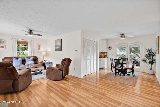 living area featuring a textured ceiling, a ceiling fan, and light wood-style floors