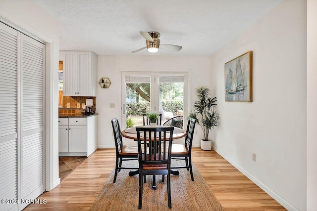 dining room featuring ceiling fan, baseboards, a textured ceiling, and light wood-style flooring