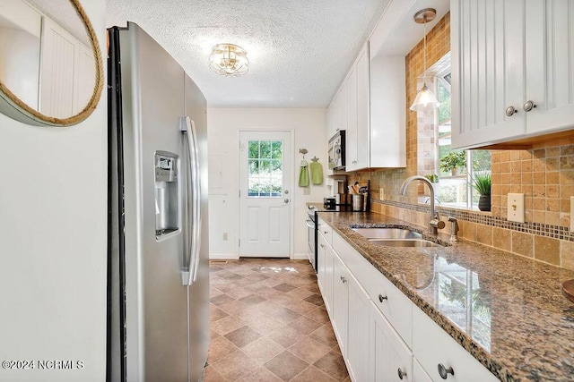 kitchen with backsplash, white cabinets, a textured ceiling, stainless steel appliances, and a sink