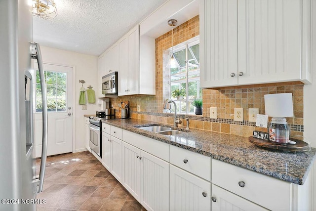 kitchen featuring decorative backsplash, white cabinetry, stainless steel appliances, and a sink