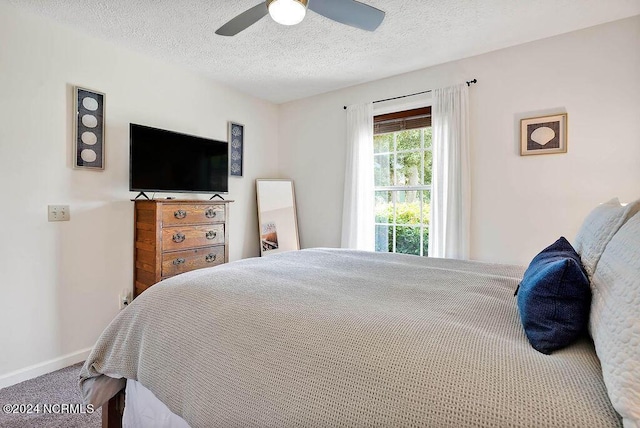 carpeted bedroom featuring a ceiling fan, baseboards, and a textured ceiling