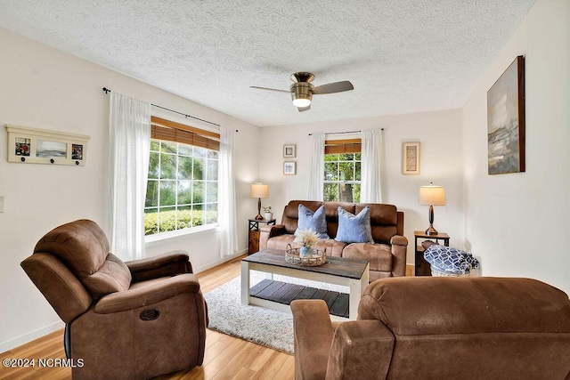 living room with light wood-type flooring, plenty of natural light, baseboards, and a ceiling fan