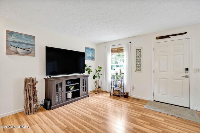 foyer featuring a textured ceiling, baseboards, and wood finished floors