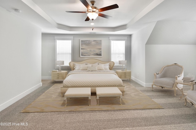 bedroom featuring a tray ceiling, carpet flooring, a ceiling fan, and baseboards