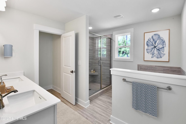 bathroom with a shower stall, wood finished floors, baseboards, and a sink