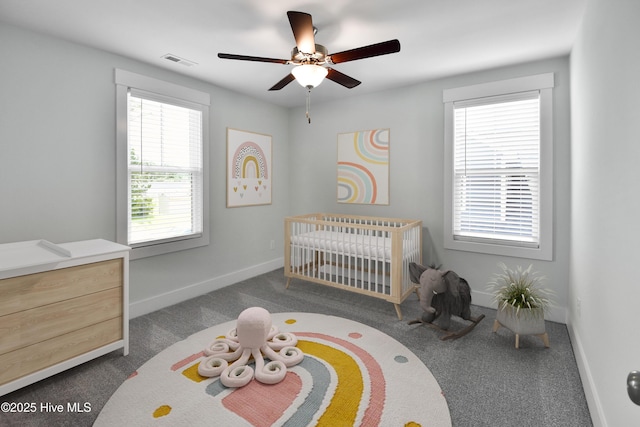 bedroom featuring visible vents, baseboards, dark carpet, a ceiling fan, and a nursery area