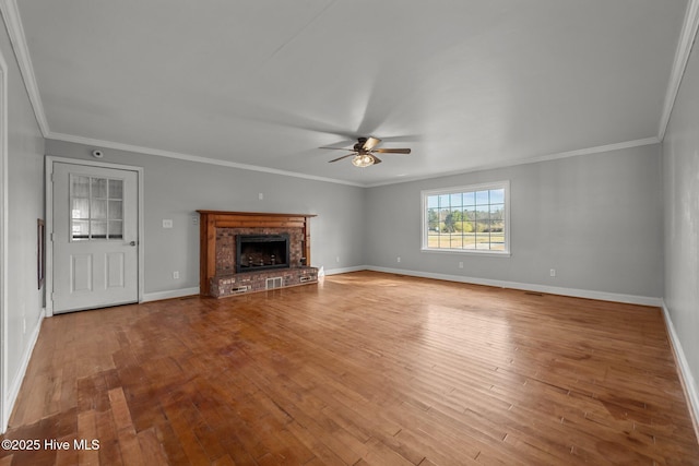 unfurnished living room with hardwood / wood-style floors, a ceiling fan, baseboards, a fireplace, and crown molding