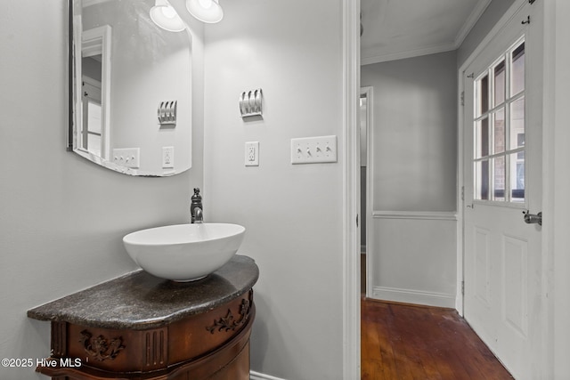 bathroom featuring vanity, wood finished floors, baseboards, and ornamental molding