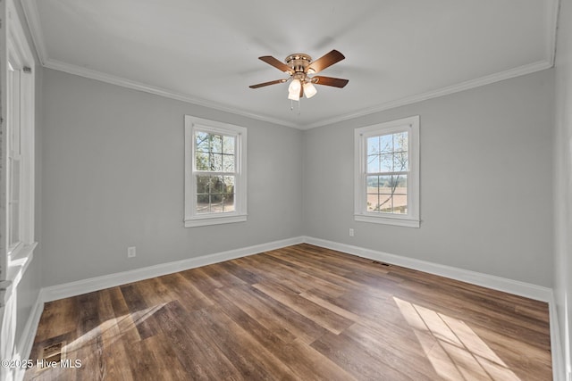 empty room featuring plenty of natural light, crown molding, dark wood-type flooring, and baseboards